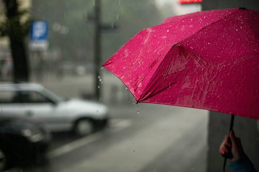 pluie qui tombe dans la rue sur un parapluie rose